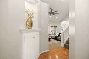 Corridor with light wood finished floors, lofted ceiling, and recessed lighting