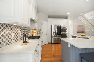 Kitchen featuring stainless steel appliances, light wood-style flooring, a large island, a breakfast bar, pantry and quartz countertops