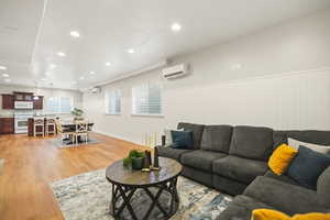 Basement living room with a wainscoted wall, recessed lighting, and light wood finished floors