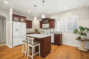 Second kitchen featuring white appliances, a breakfast bar, arched walkways, decorative light fixtures, and a center island