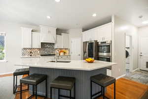 Kitchen featuring white cabinets, a kitchen breakfast bar, stainless steel appliances, quartz counters, and recessed lighting