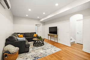 Basement living area featuring light wood-style flooring, recessed lighting, and a wainscoted wall