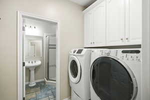 Laundry area with stone finish flooring, washing machine and clothes dryer, and cabinet space