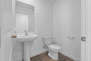 Half bathroom with toilet and dark wood-style flooring