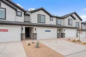 Traditional home featuring a garage, stucco siding, concrete driveway, and a tiled roof