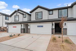 View of front of home featuring stone siding, stucco siding, an attached garage, driveway, and a tiled roof