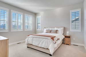 Bedroom featuring light colored carpet and a textured ceiling
