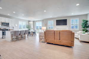 Living room featuring light wood finished floors, a textured ceiling, and hanging lights