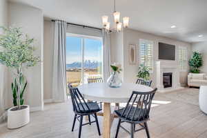 Dining space featuring light wood-type flooring, a glass covered fireplace, and suspended lighting