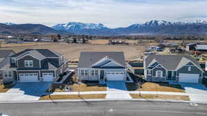 View of front of property featuring driveway, a residential view, stone siding, and a mountain view