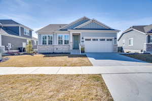 Craftsman-style home featuring stone siding, board and batten siding, driveway, a front lawn, and an attached garage