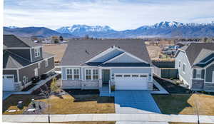 View of front of property with stone siding, driveway, roof with shingles, a mountain view, and an attached garage