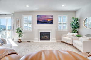 Living room with a glass covered fireplace, light wood finished floors, and recessed lighting