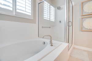 Full bathroom featuring a shower stall, a garden tub, and tile patterned flooring