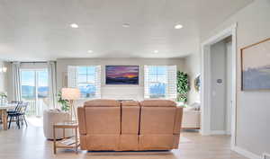 Living room featuring light wood-type flooring, a mountain view, recessed lighting, and a textured ceiling