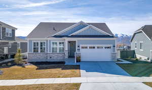 Craftsman-style home featuring stone siding, board and batten siding, driveway, and roof with shingles