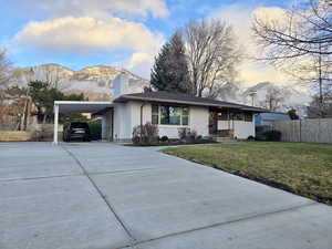 View of front of home featuring brick siding, driveway, a carport, a chimney, and a mountain view