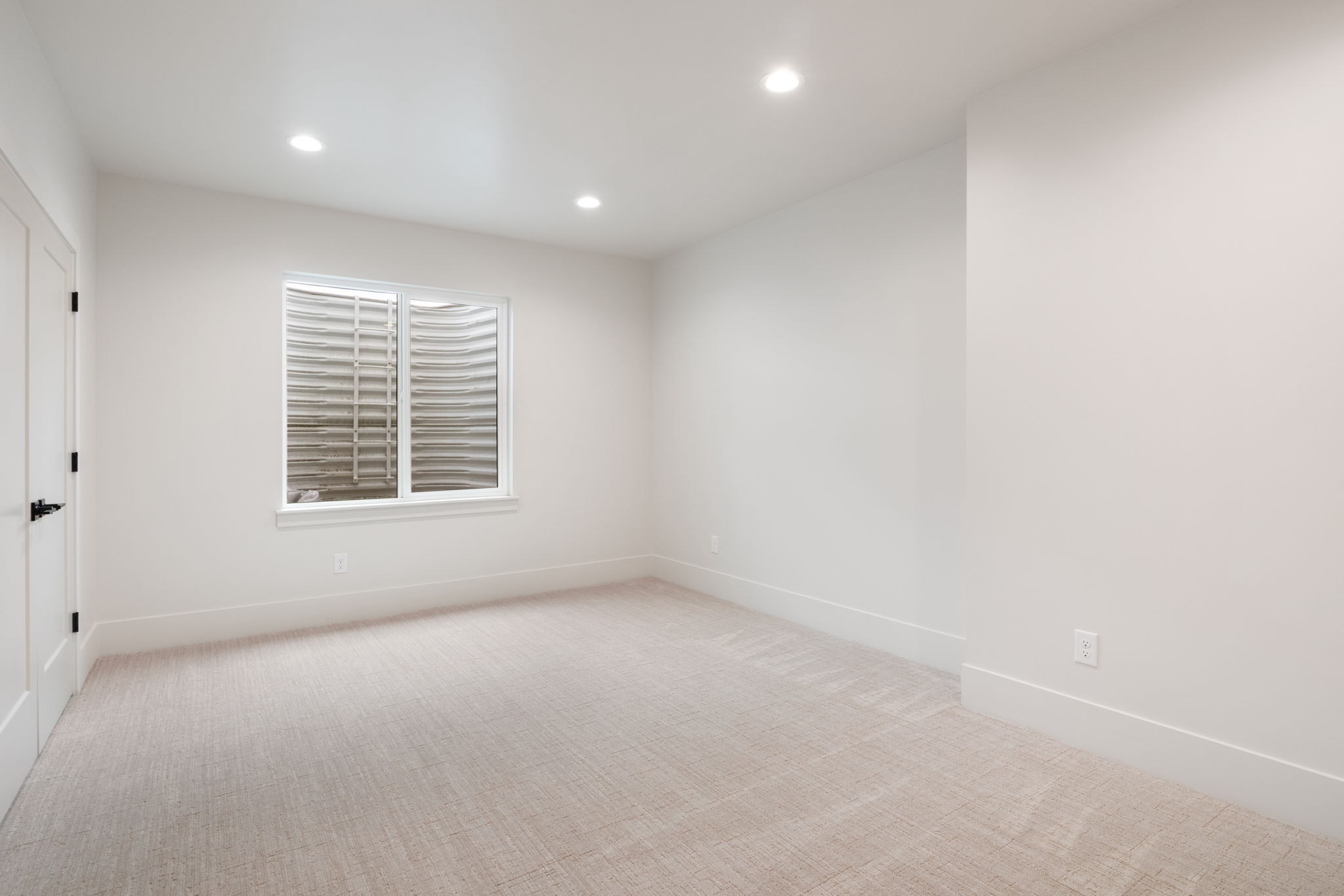 Bright, neutral interior space featuring recessed lighting, a white framed window, and light-toned carpet flooring
