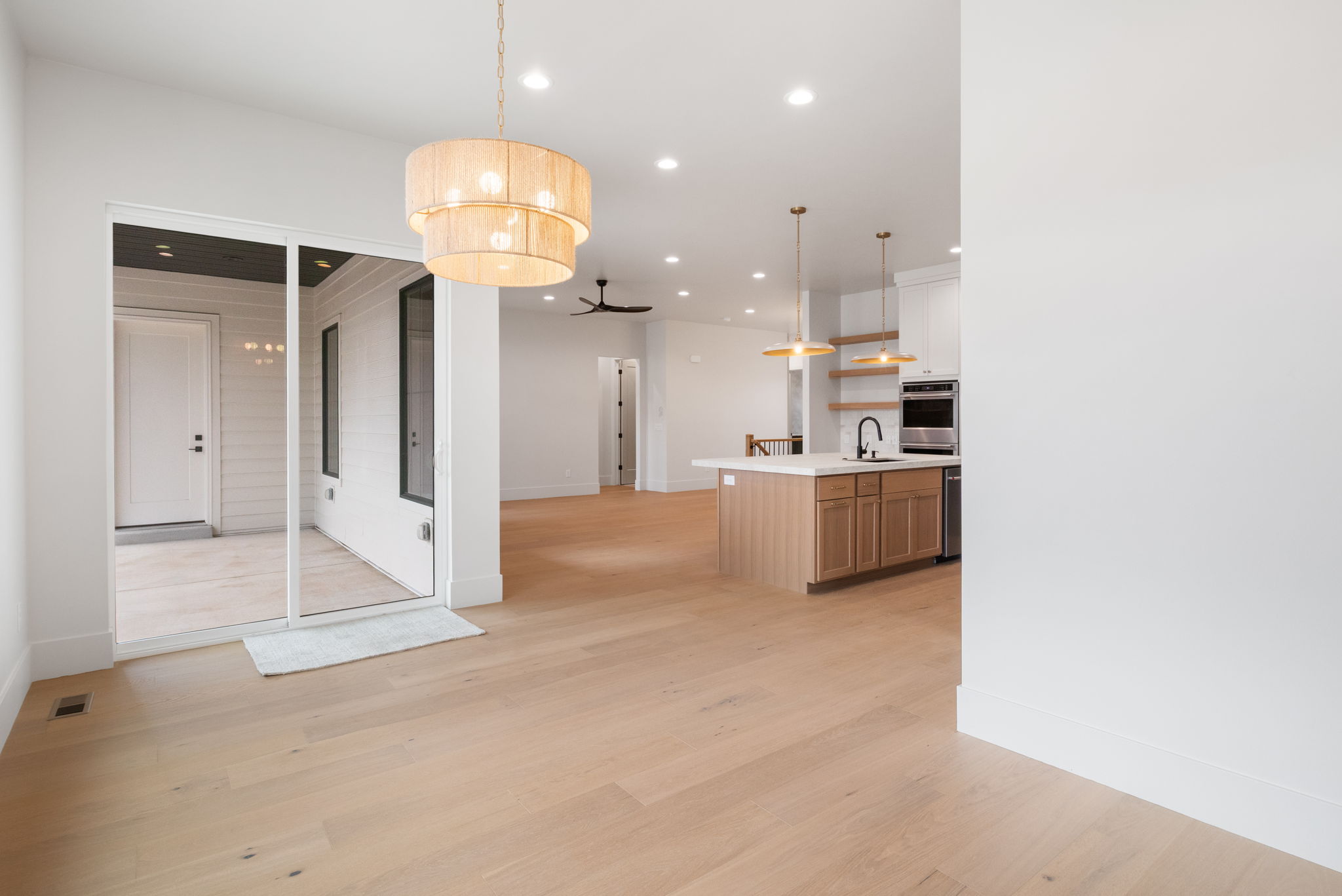 Open-concept living area with wood-finish flooring, a tiered pendant light fixture, and sliding glass doors
