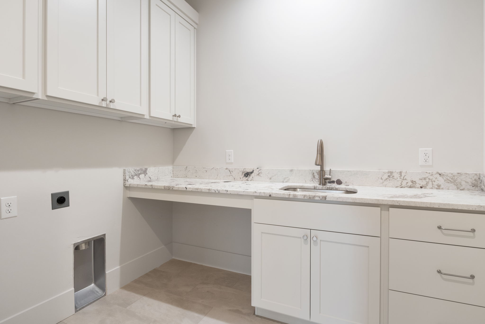 Utility room featuring a built-in sink with a gooseneck faucet, light-toned cabinetry, stone countertops, and tile flooring