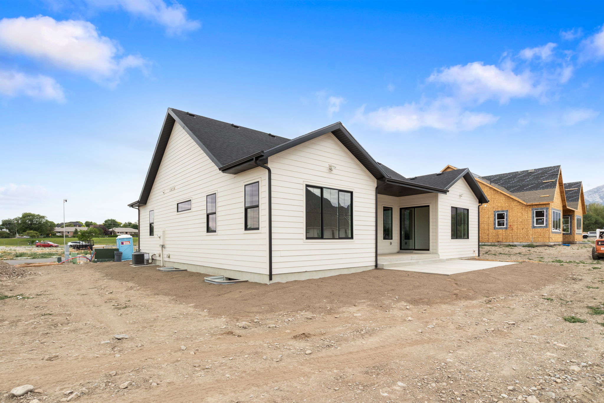 New construction featuring a white horizontal siding exterior, dark framed windows, a dark shingled roof, a covered patio, and a concrete patio