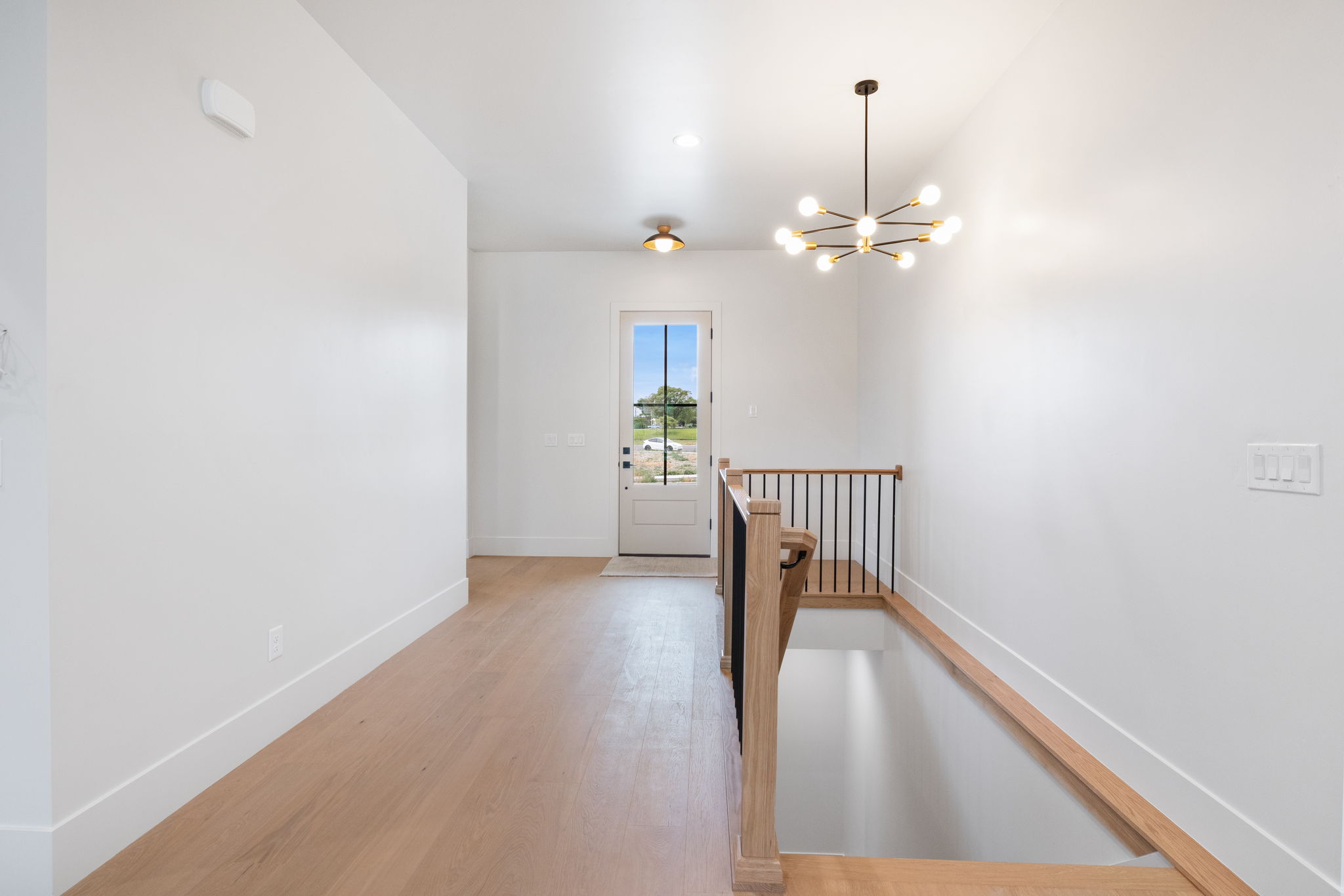 Entryway featuring light wood-finish flooring, a modern sputnik chandelier, and a white paneled door with glass inserts