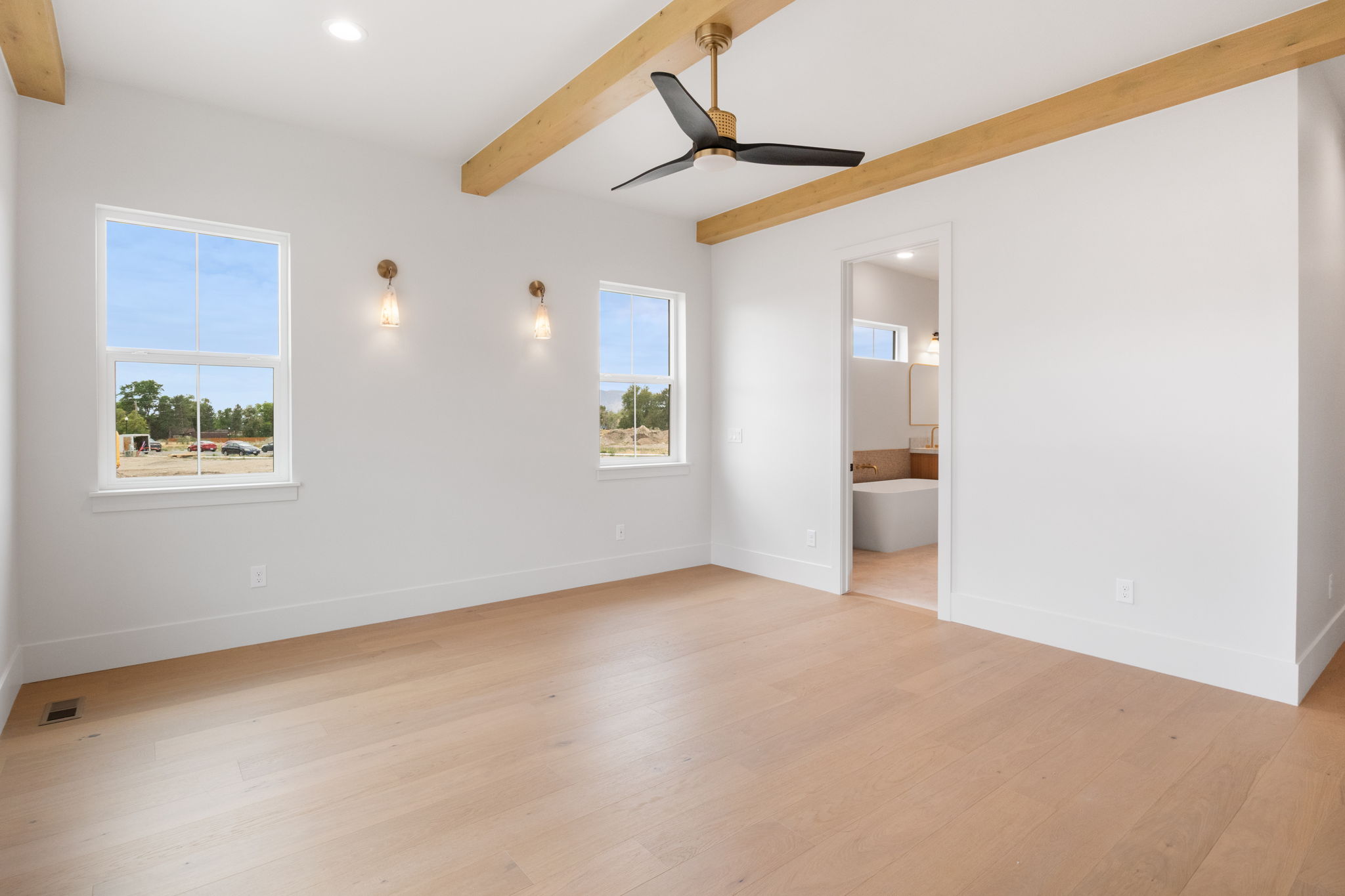 Spacious room featuring exposed wood beams, a modern ceiling fan with brass accents, and recessed lighting