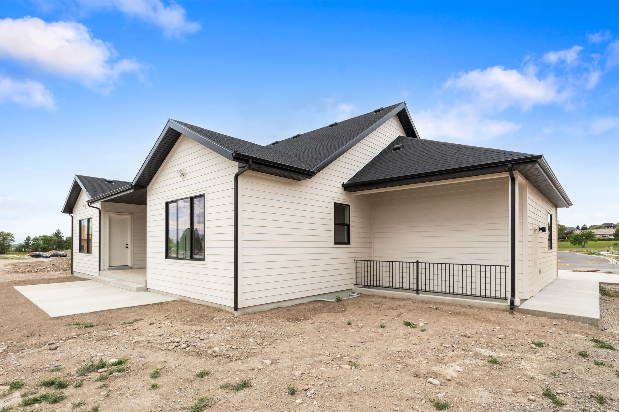 Newly constructed residence featuring light-colored horizontal siding, a dark shingle roof, and black-framed windows