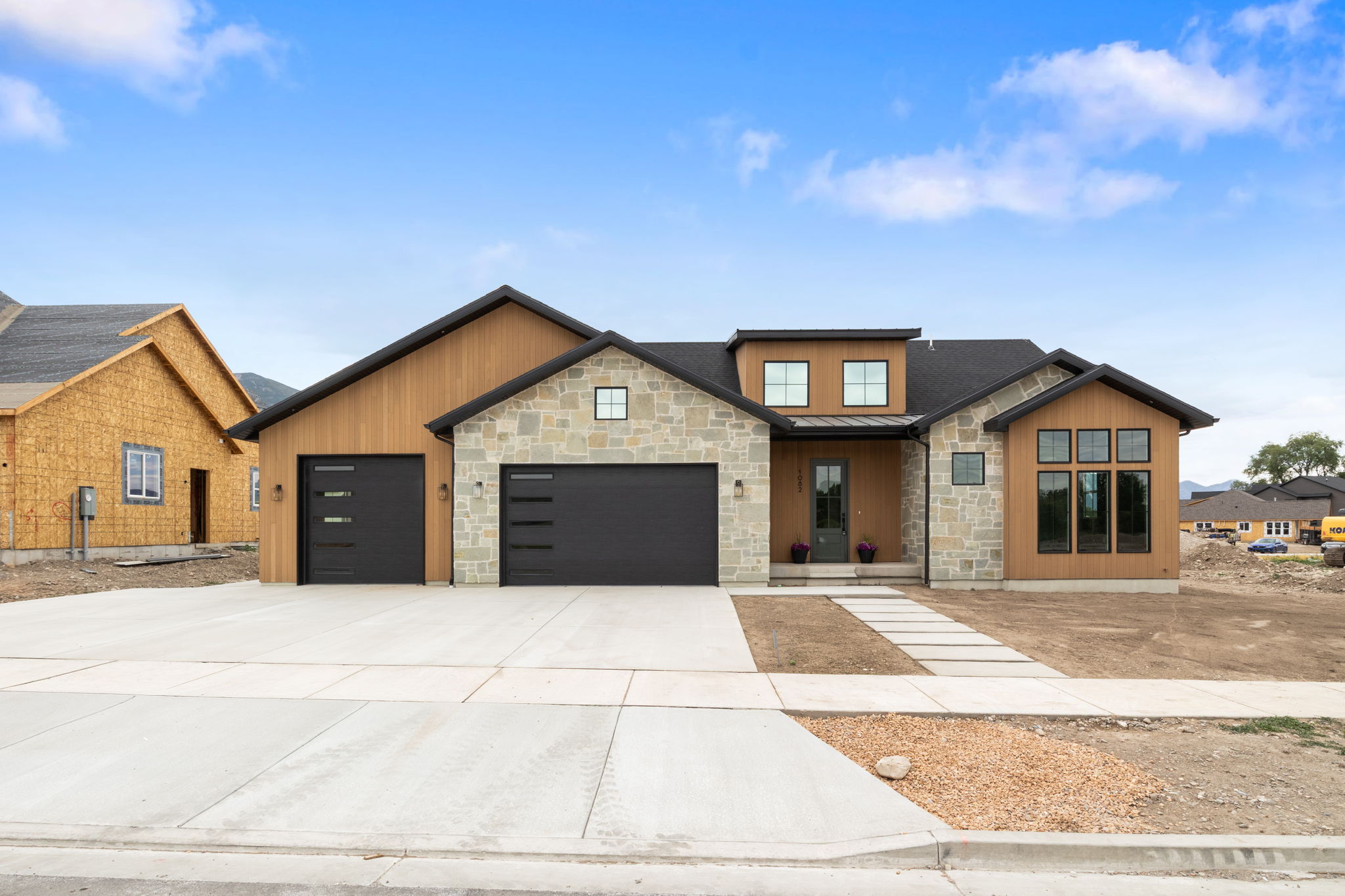 Contemporary exterior featuring stone accents, vertical wood-finish siding, and a dark shingled roof