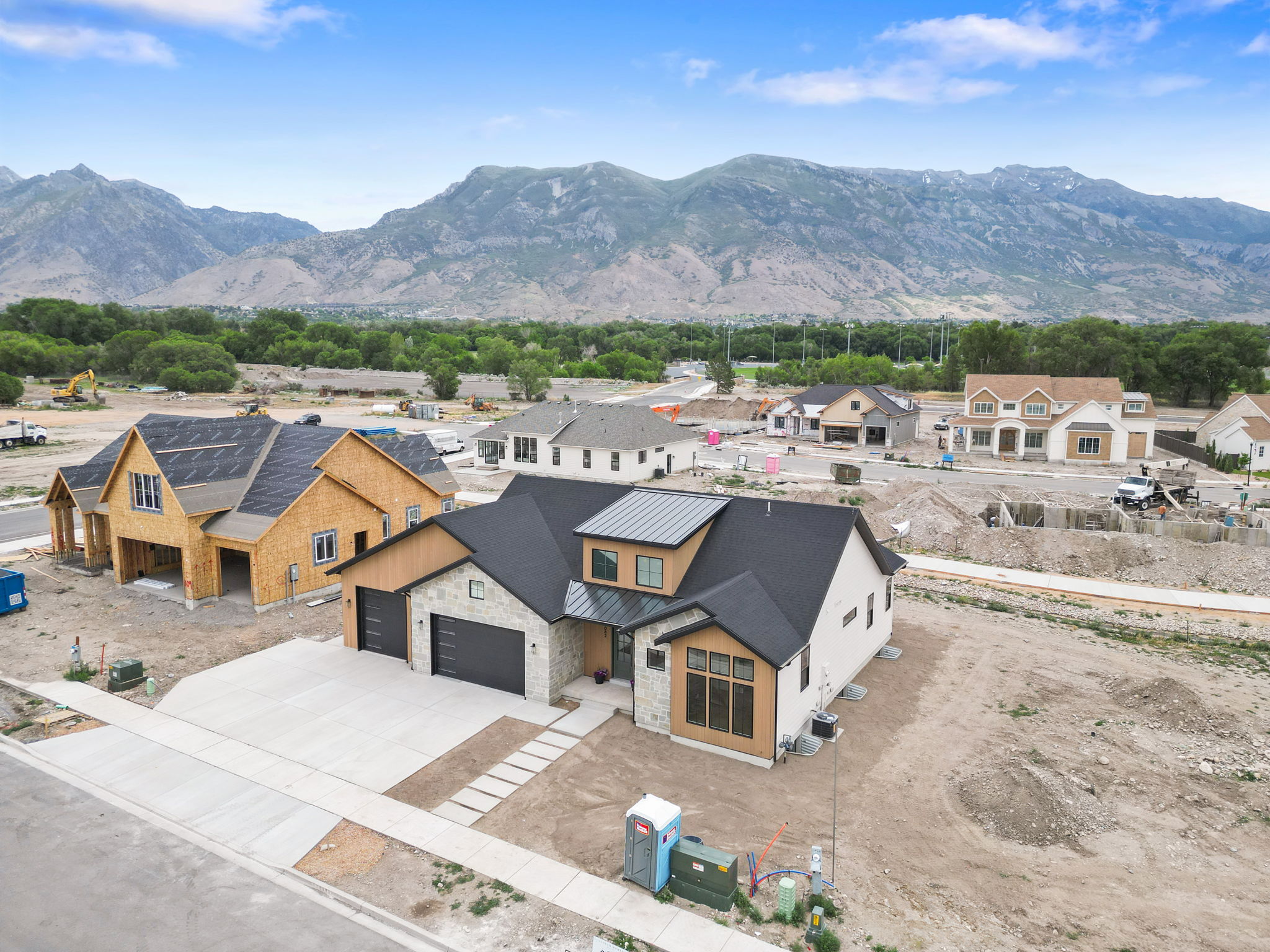 Contemporary residence featuring a black roof, stone accents, and varied siding