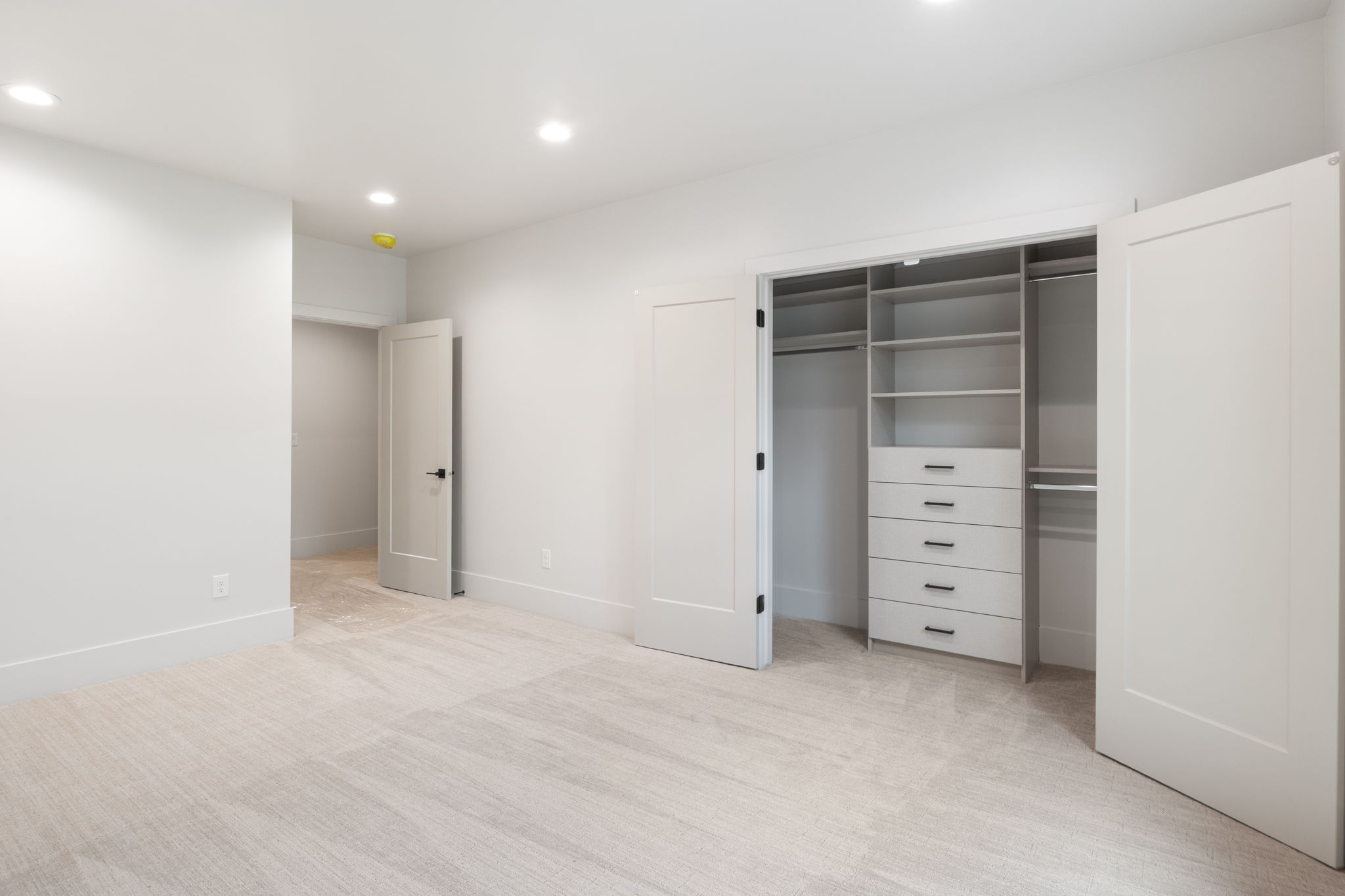 Carpeted room with recessed lighting and a built-in closet system featuring shelving and drawers