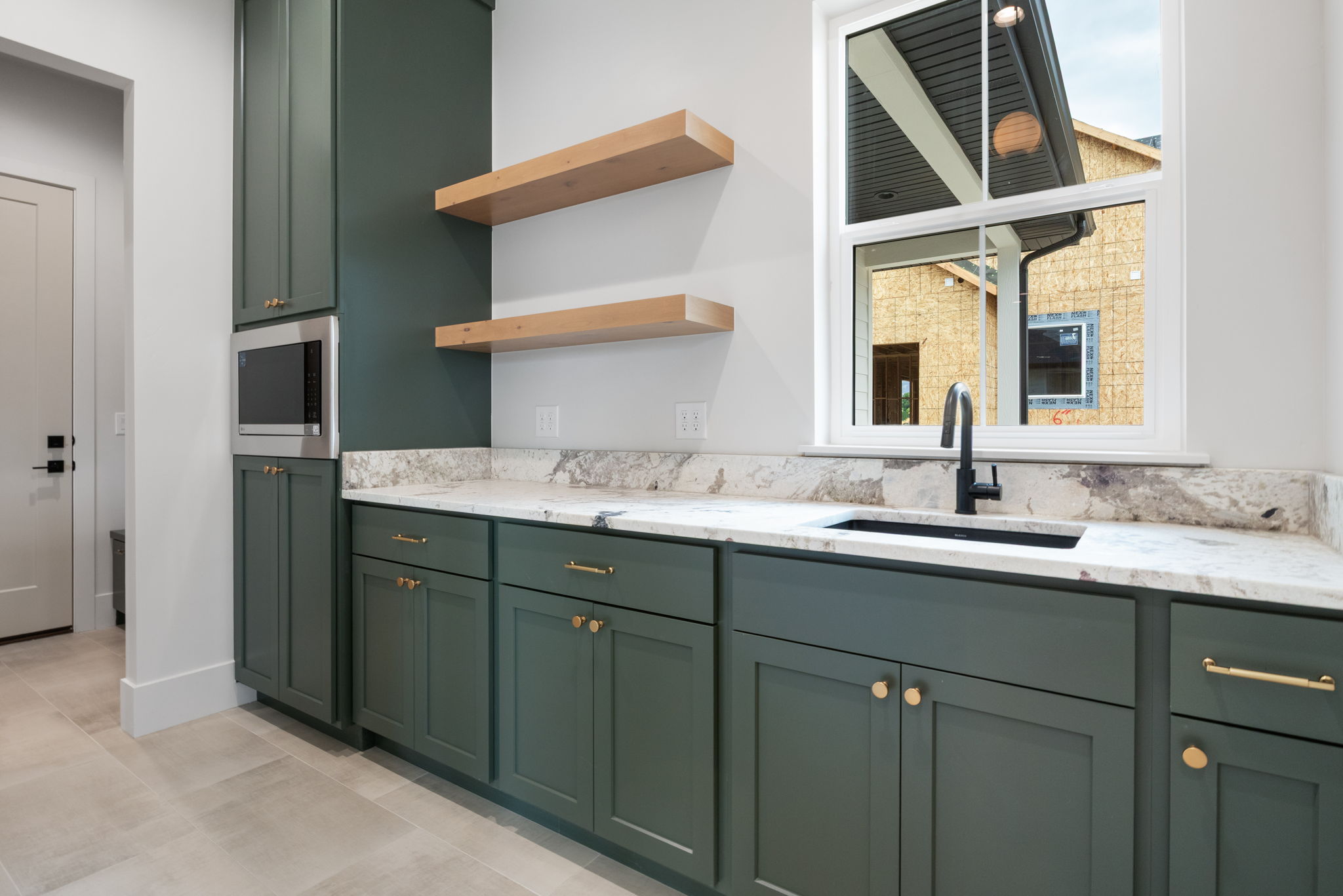 Built-in cabinetry with a dark green finish, brass hardware, and a fully integrated microwave