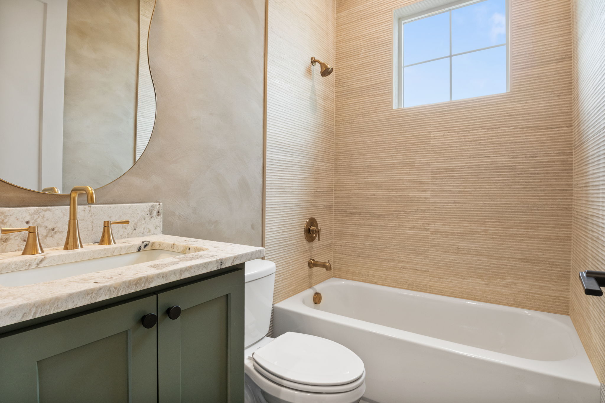 Bathroom featuring a vanity with an integrated sink, stone countertop, and brass-finish hardware