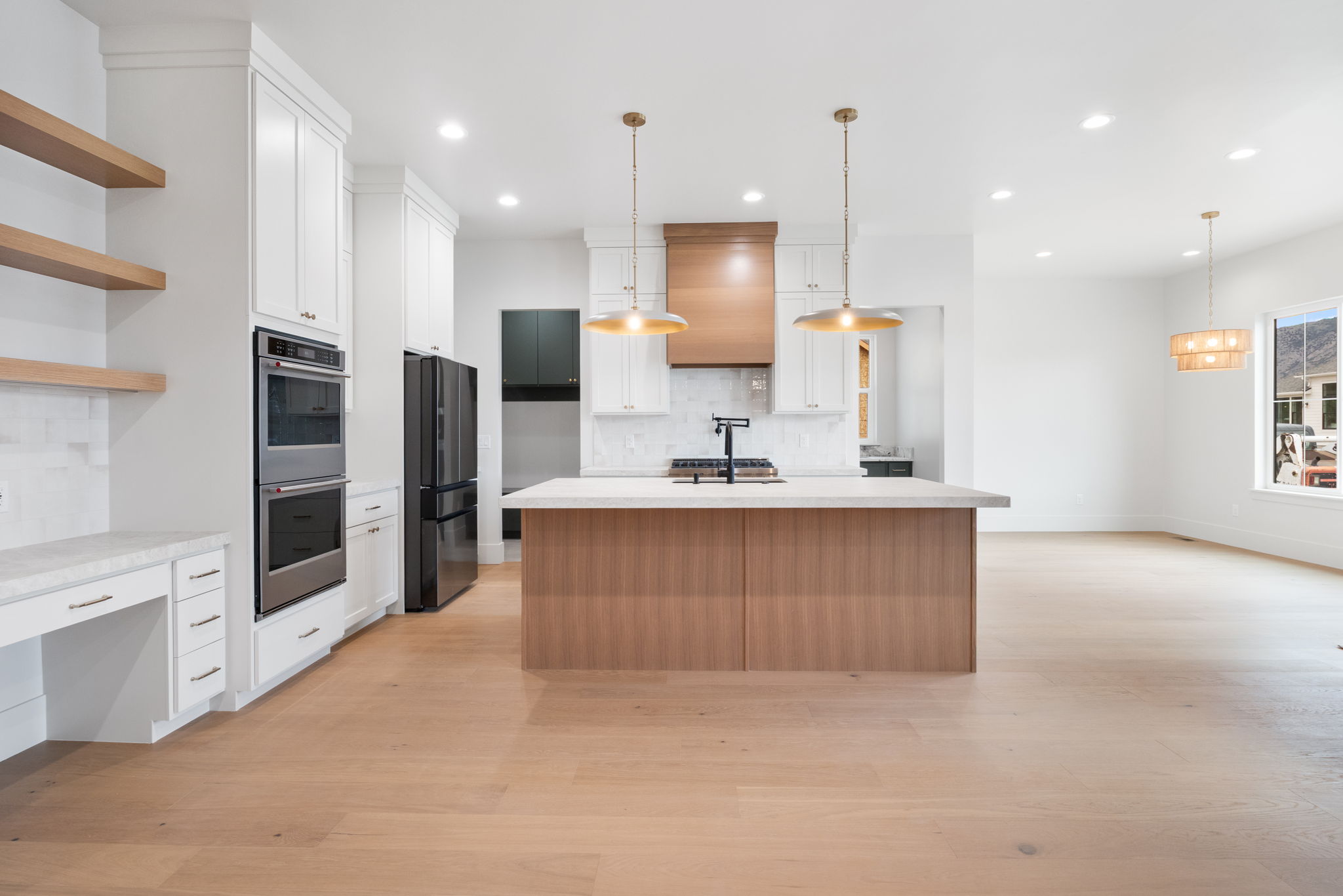 Contemporary kitchen featuring a large central island with a light wood-finish base, white countertop, and two pendant light fixtures