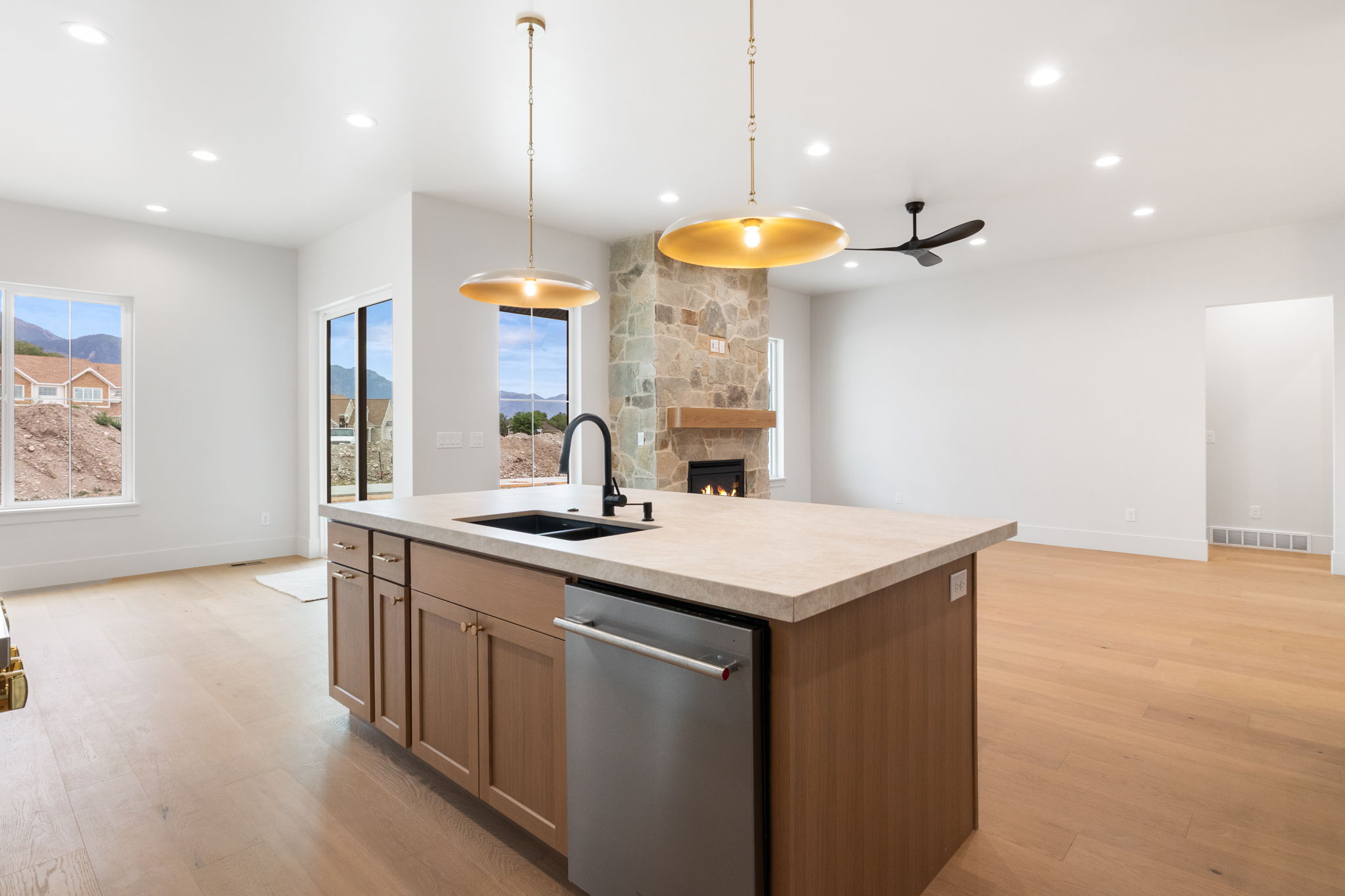 Kitchen island with integrated sink and dishwasher, featuring pendant lighting and light wood-finish cabinetry