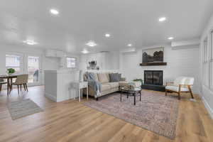 Living room with a large fireplace, light wood-type flooring, and recessed lighting