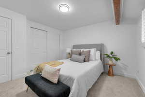 Carpeted bedroom with a closet and beamed ceiling