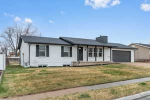 Ranch-style home with brick siding, a front yard, a chimney, concrete driveway, and an attached garage