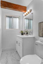 Bathroom with vanity, light marble finish floors, and beam ceiling