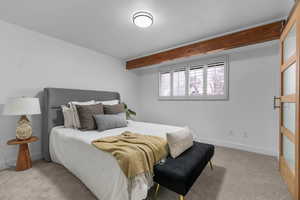 Bedroom with light carpet and beamed ceiling