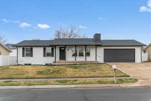 Ranch-style home featuring a porch, driveway, brick siding, and a garage