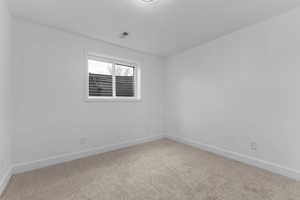 Spare room with baseboards and light colored carpet