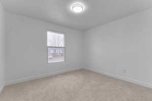 Empty room featuring baseboards and light carpet