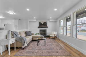 Living room featuring a large fireplace, recessed lighting, and light wood-style floors