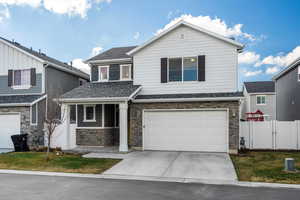 View of front of house with stone siding, a garage, concrete driveway, and roof with shingles