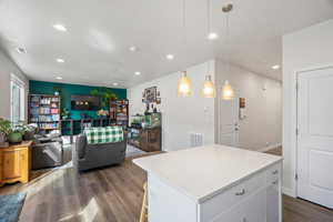 Kitchen with a kitchen island, dark wood-type flooring, open floor plan, a kitchen breakfast bar, and white cabinets