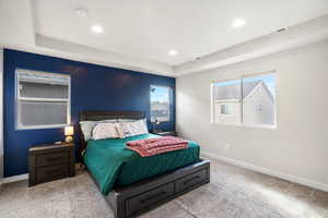 Bedroom with light carpet, a tray ceiling, and recessed lighting