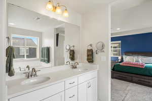 Bathroom with double vanity, ensuite bathroom, light colored carpet, and recessed lighting