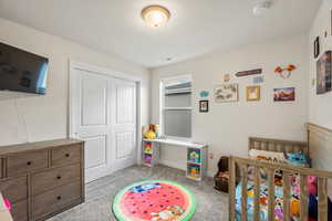 Bedroom featuring a closet, light carpet, and a nursery area