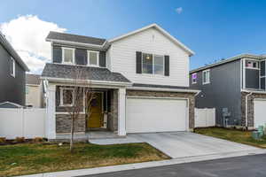 Traditional-style home featuring roof with shingles, concrete driveway, an attached garage, and stone siding